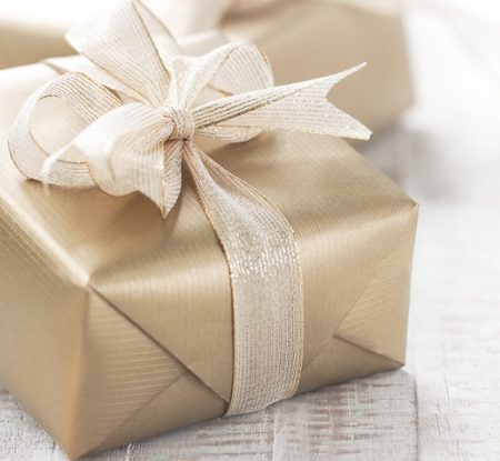Golden gift boxes with beautiful ribbon and bow on a bright shiny background, holiday concept, horizontal with copy space